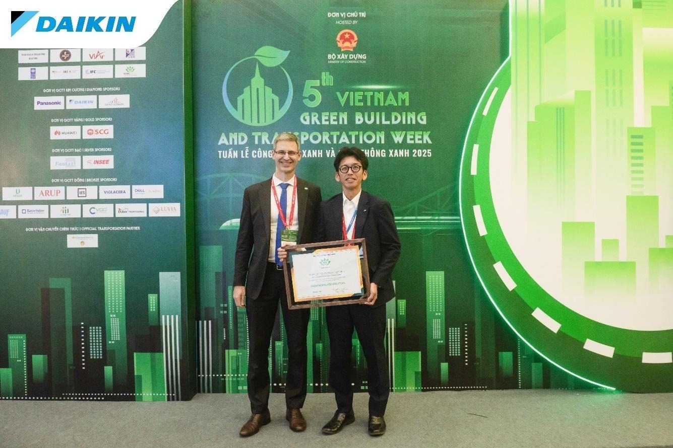 Two men standing in front of a green wallAI-generated content may be incorrect.