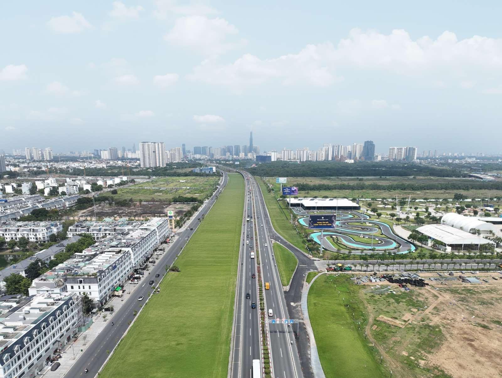 A highway with a green road and buildingsAI-generated content may be incorrect.