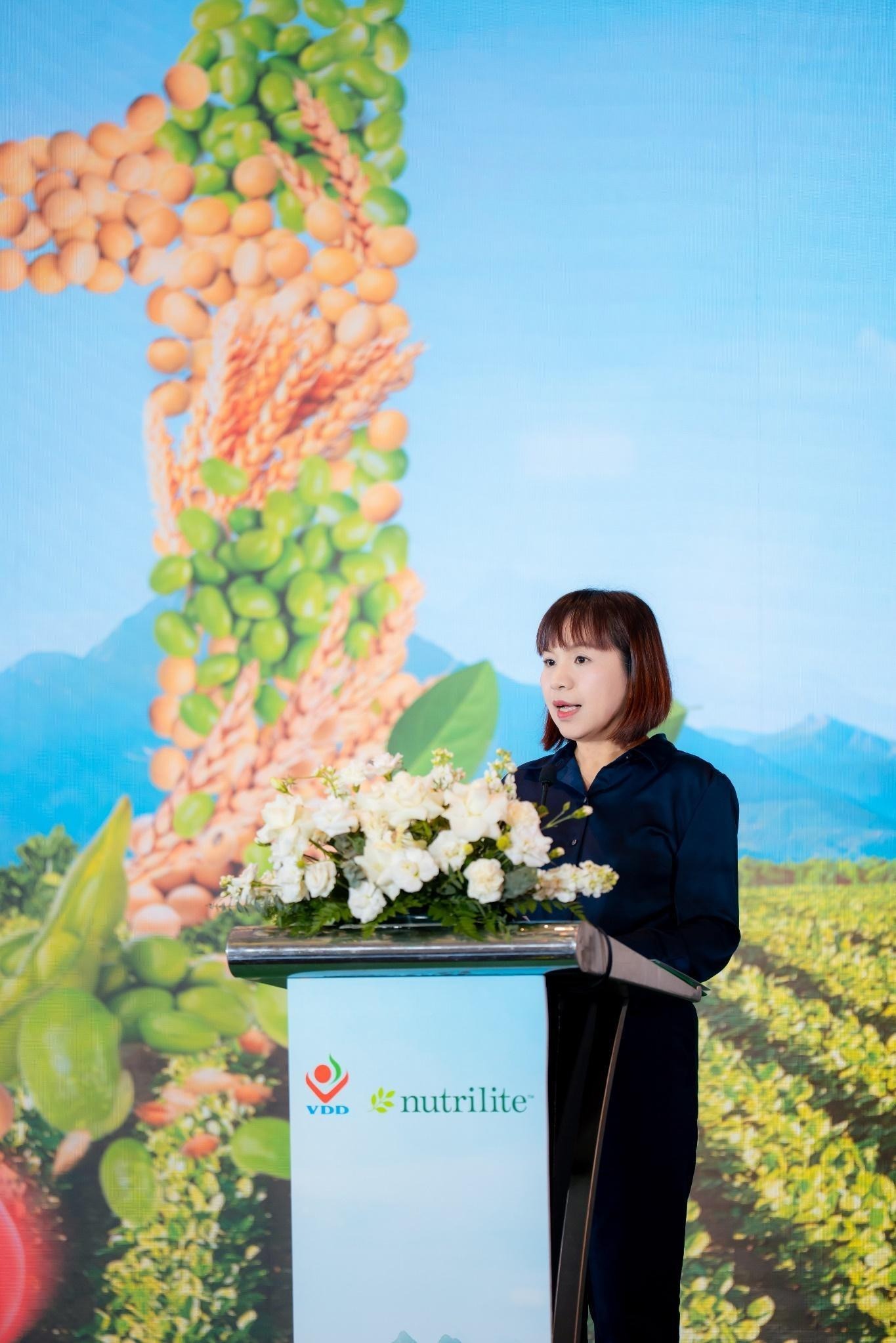 A person standing behind a podium with flowersAI-generated content may be incorrect.